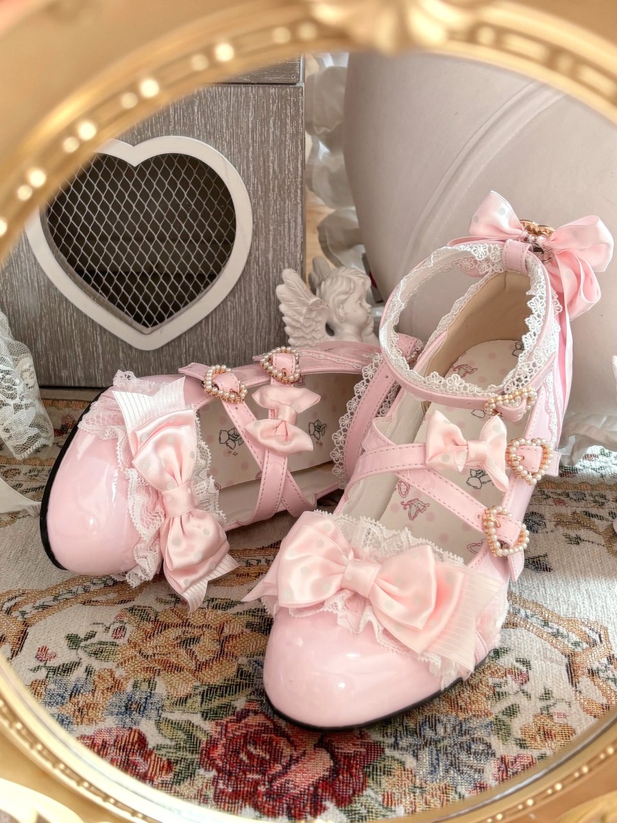 Pink decorative shoes with bows on a floral surface