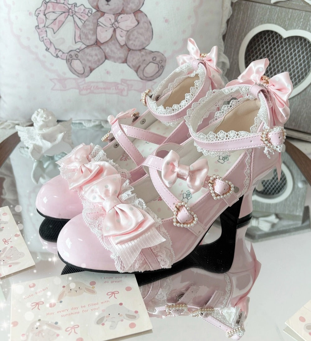 Pink high-heeled shoes with decorative bows and lace on a white surface.
