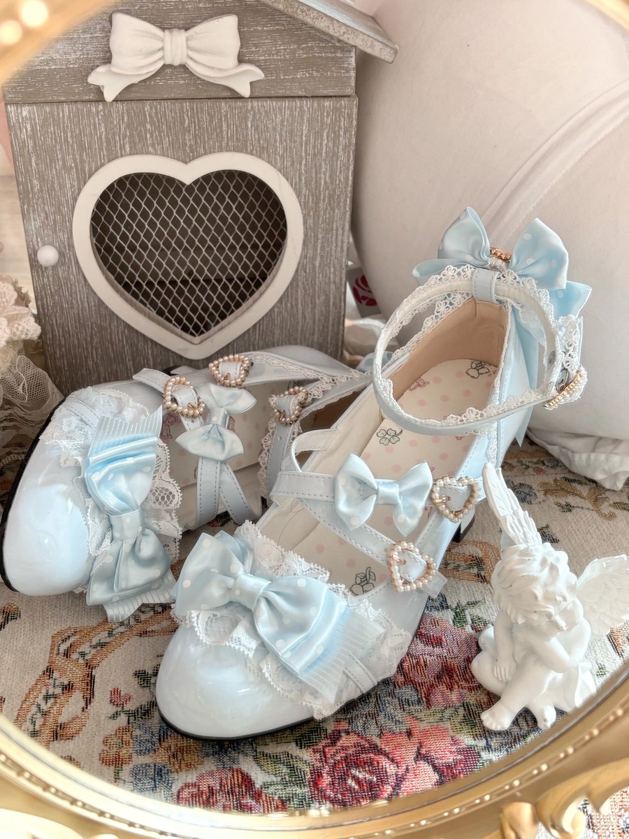 Pair of blue decorative shoes with bows and heart details on a floral surface.
