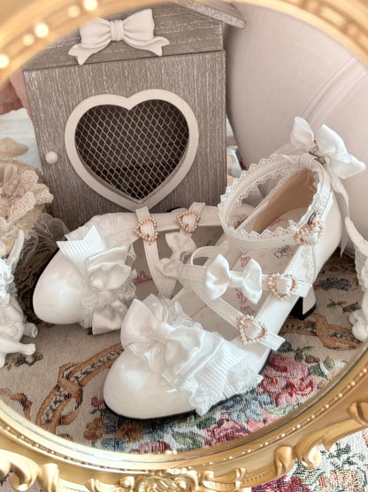 White lace-up shoes with decorative bows and pearls on a floral-patterned surface.