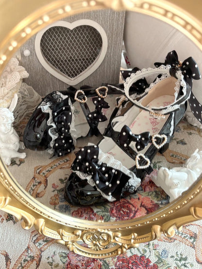 Black shoes with heart and bow details on a decorative surface