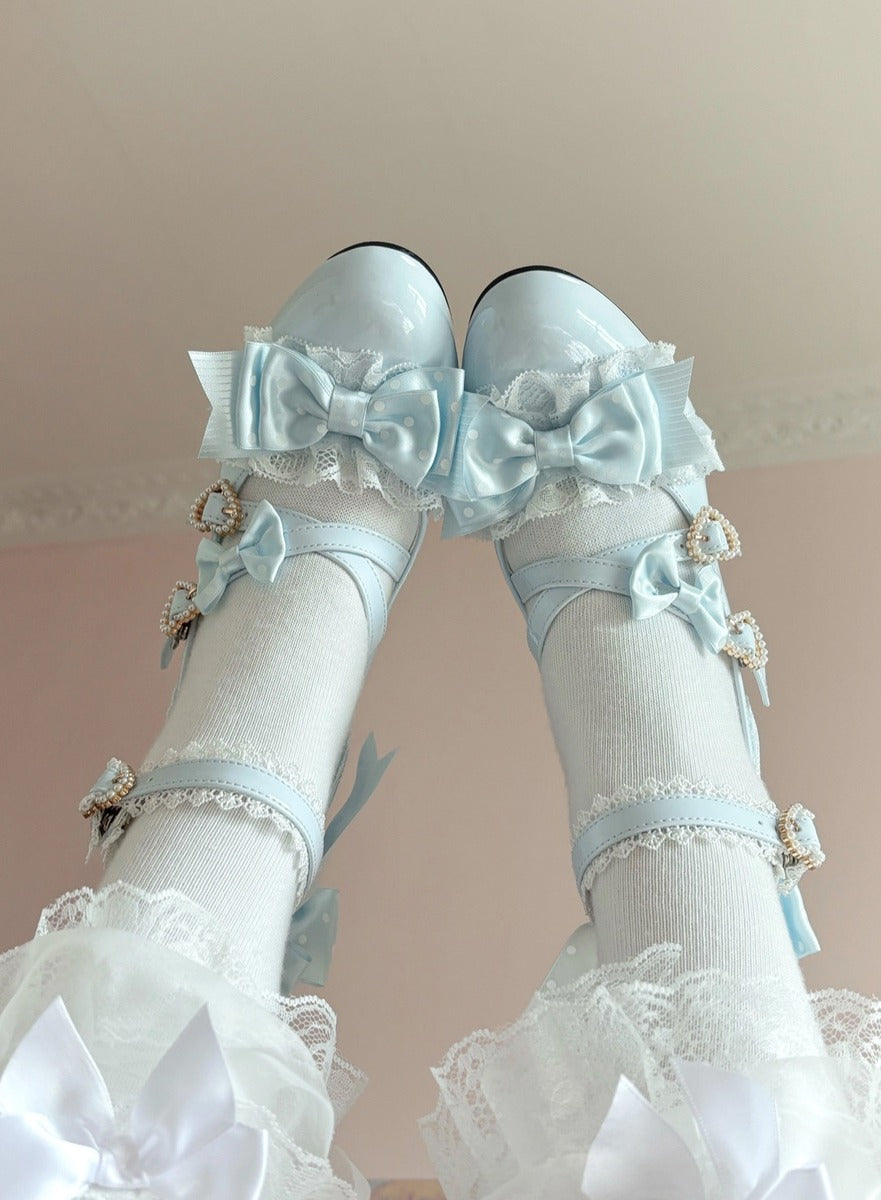 Pair of light blue shoes with decorative bows and white stockings on a neutral background