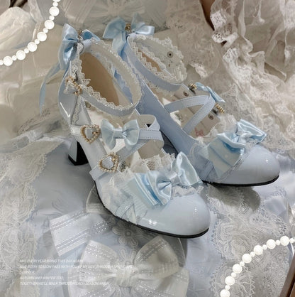 Pair of white high-heeled shoes with decorative bows on a lace background