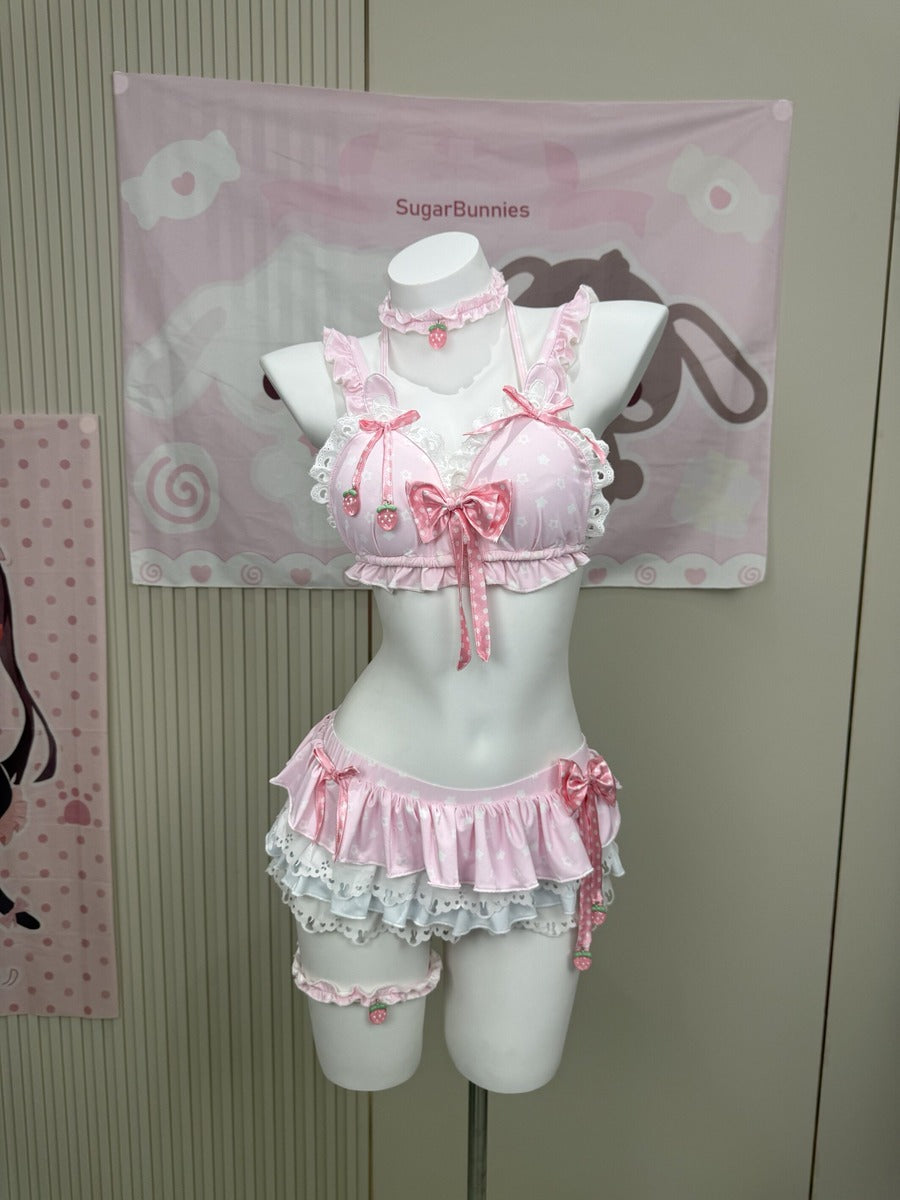 A pink Lolita-style two-piece lingerie set with ruffles, lace, and bows, displayed on a white mannequin torso. The set includes a cropped top with strawberry details and a matching ruffled bottom.