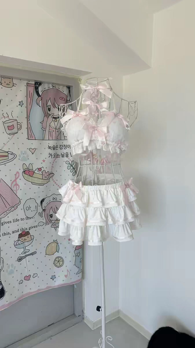 A white and pink Lolita-style lingerie set displayed on a clear wire dress form. The set includes a ruffled crop top with matching ruffled shorts, decorated with pink bows and lace.