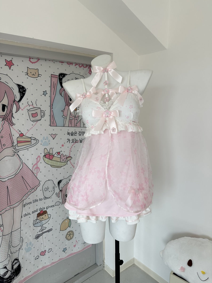A pink and white Lolita-style lingerie set displayed on a white mannequin torso in a room corner. The set features a white lace halter top with pink satin bows and a sheer pink ruffled skirt.