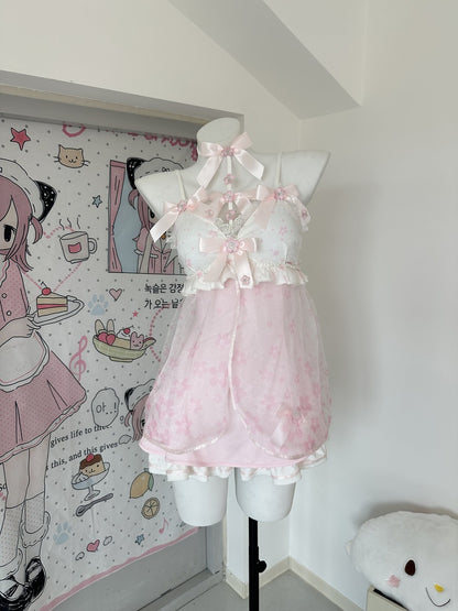A pink and white Lolita-style lingerie set displayed on a white mannequin torso in a room corner. The set features a white lace halter top with pink satin bows and a sheer pink ruffled skirt.