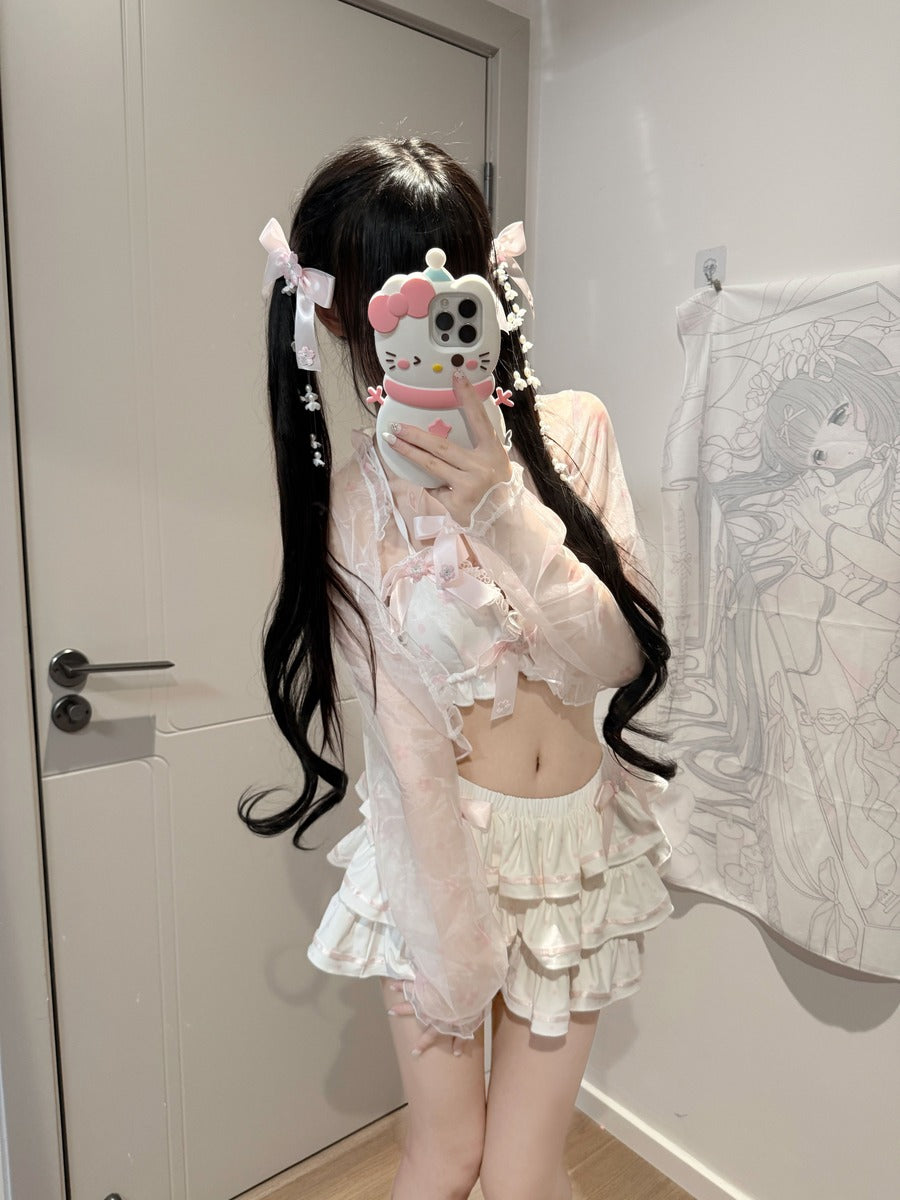A person taking a mirror selfie in a room, wearing a light pink and white frilly outfit with a long black wavy wig and a Hello Kitty phone case.