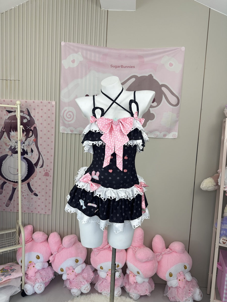 A black and pink polka-dot Lolita-style dress displayed on a white mannequin torso in a room decorated with anime-themed wall hangings and pink plush toys.