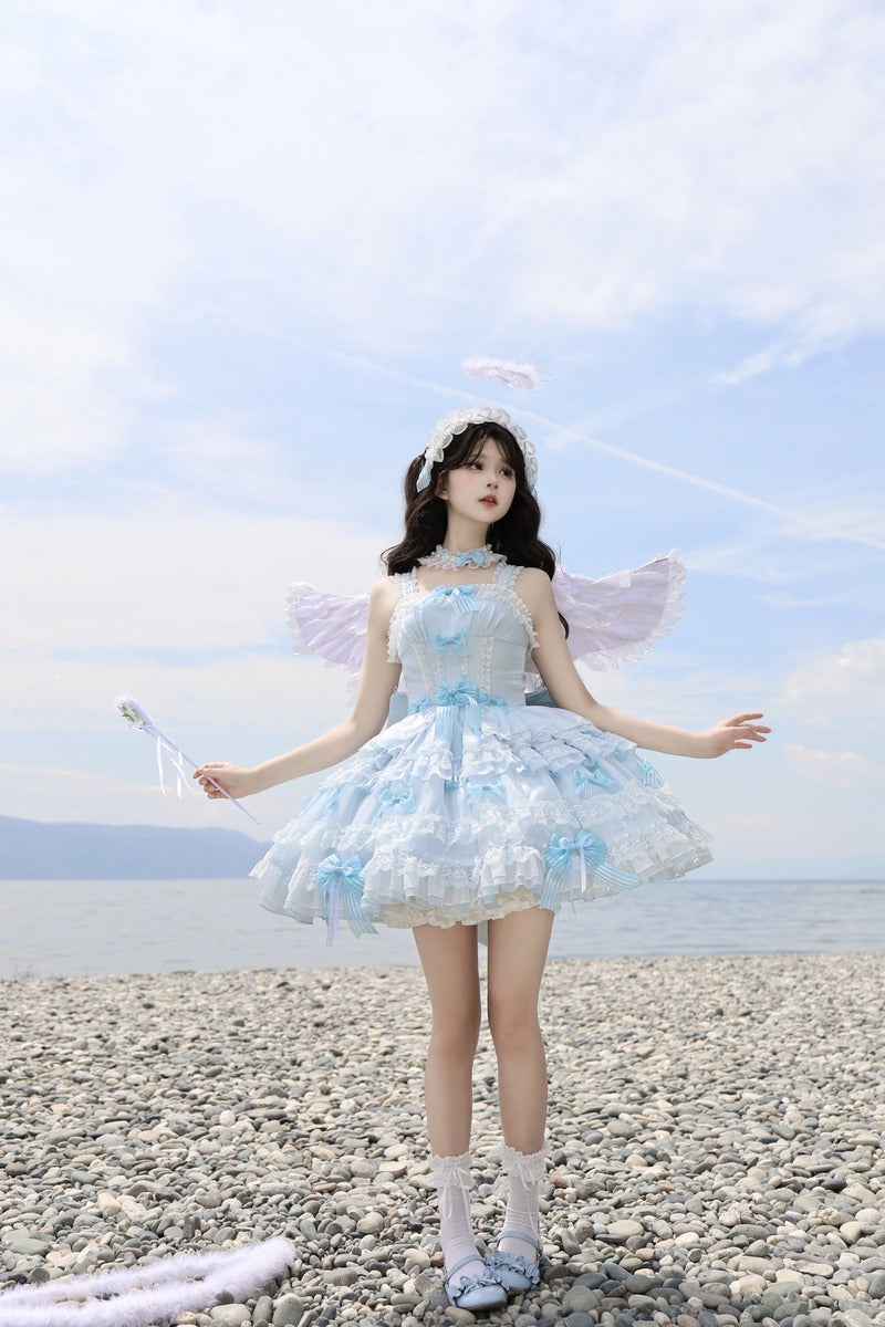 Person in a fairy costume standing on a pebbly beach with a clear sky.