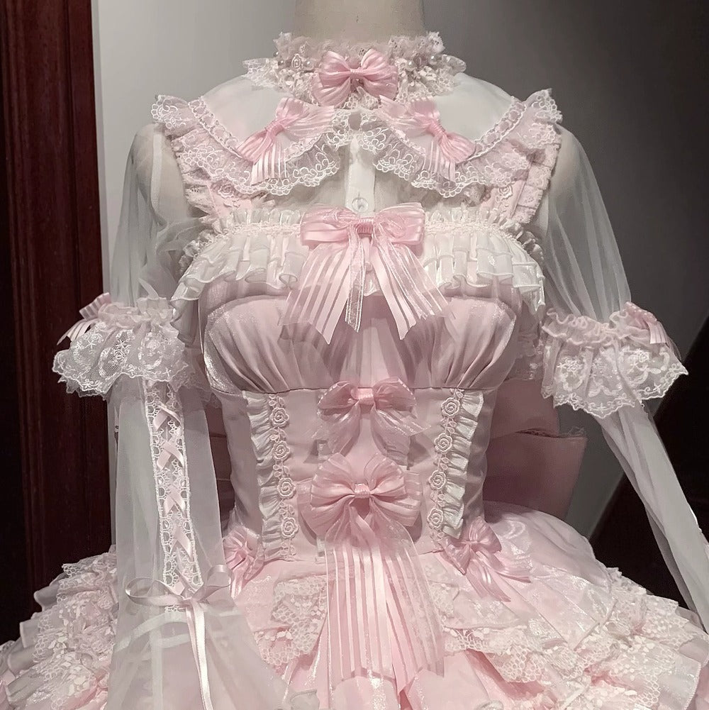 Delicate pink and white dress with lace details on a mannequin against a dark background