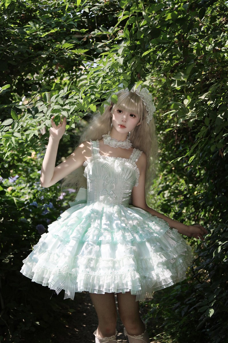 Person wearing a light blue dress with ruffles standing in a forest setting