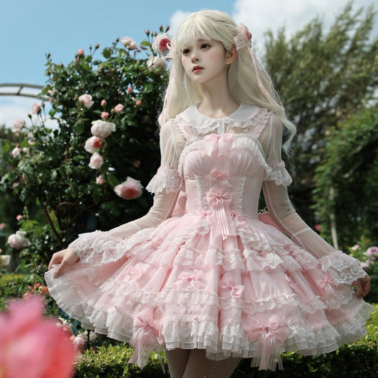 Person in a pink lolita dress standing in a garden with flowers and trees.