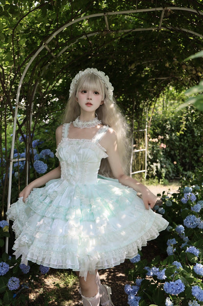 Woman in a white floral dress standing in a garden with flowers and an archway.