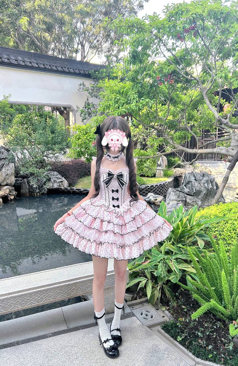 Person wearing a pink and black dress with ruffles in a garden setting
