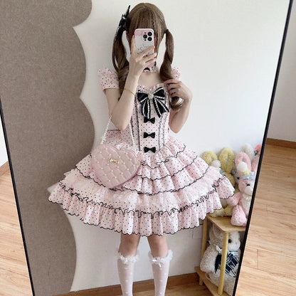 Person wearing a pink polka dot dress with black details, standing in front of a mirror.