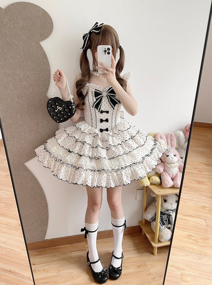 Person wearing a white dress with black bows in front of a mirror.