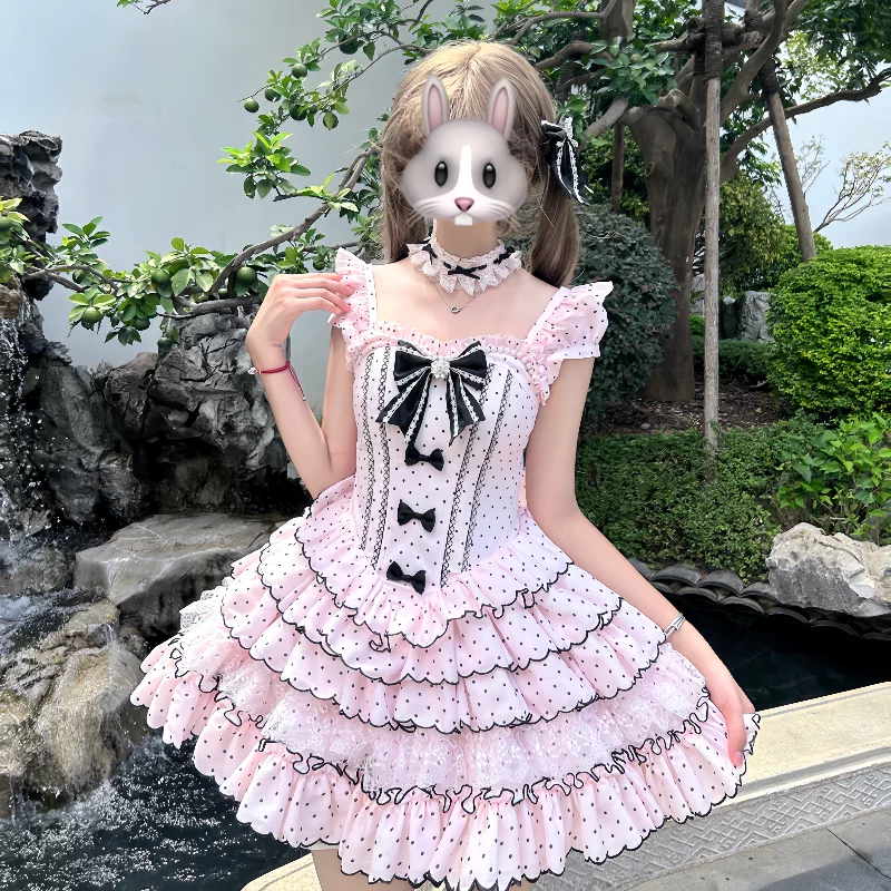 Person wearing a pink polka dot dress with black bows outdoors.
