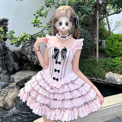 Person wearing a pink polka dot dress with black bows outdoors.