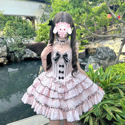 Person wearing a polka dot dress with black bows in a garden setting