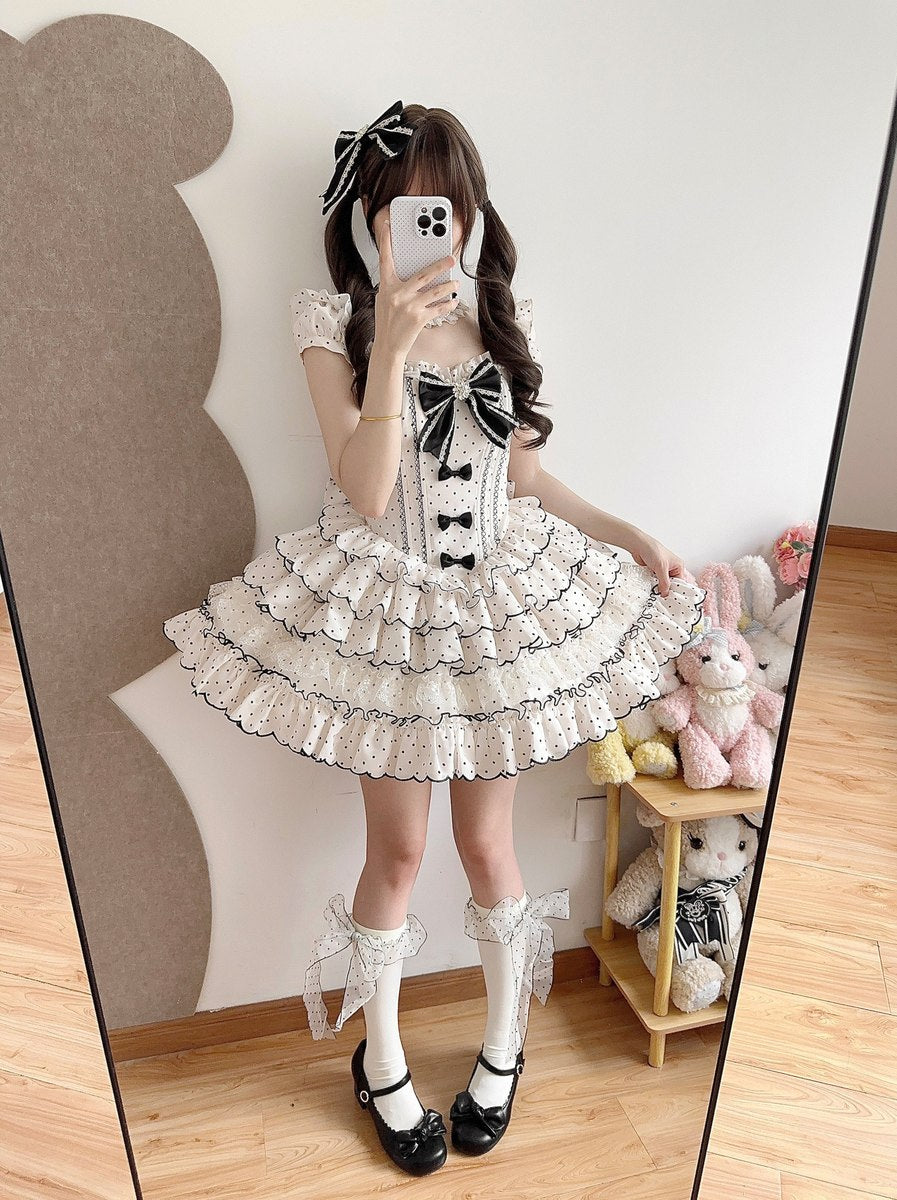 Person wearing a white and black dress with a bow, standing in front of a mirror.