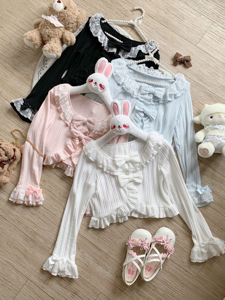 lolita style cardigan set with dresses, a teddy bear, and shoes on a wooden floor.