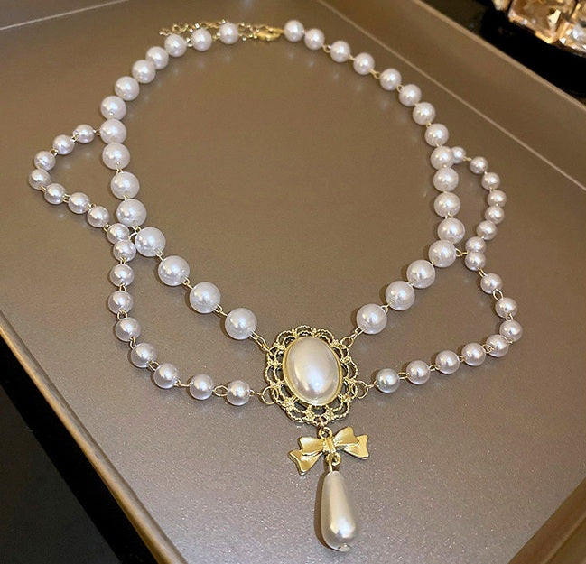 Pearl necklace with a decorative pendant on a neutral background