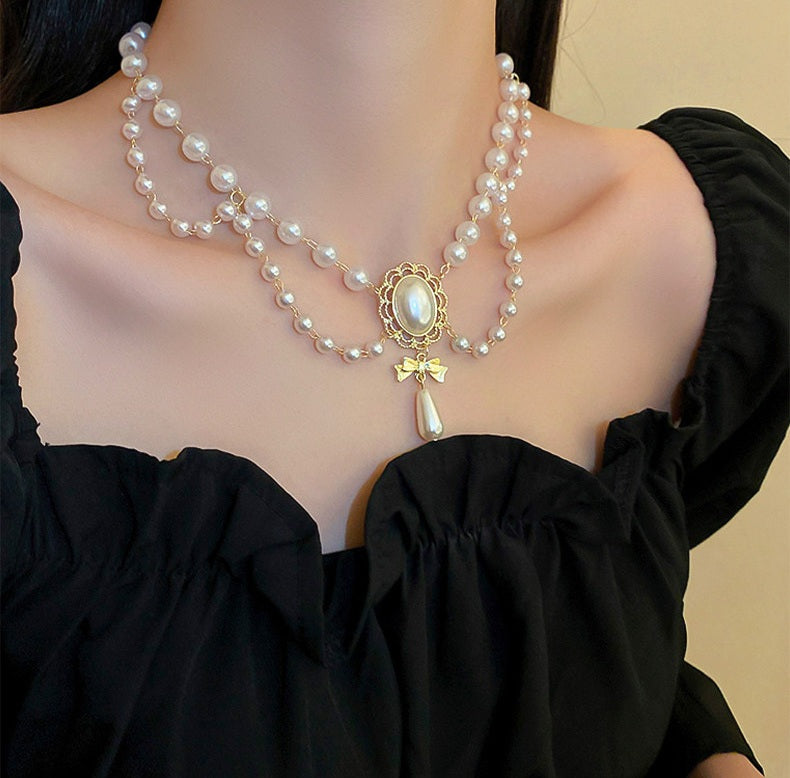 Pearl necklace with a gold pendant on a black top