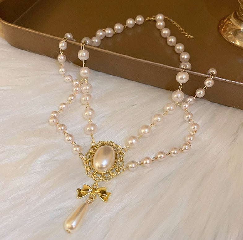 Pearl necklace with a decorative pendant on a white surface