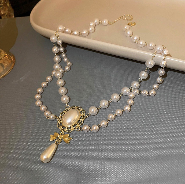 Pearl necklace with a gold pendant on a gray surface