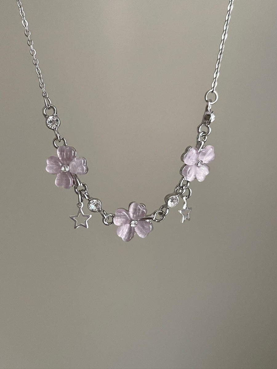 Necklace with pink floral charms and clear beads on a plain background