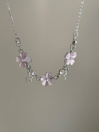 Necklace with pink floral charms and clear beads on a plain background