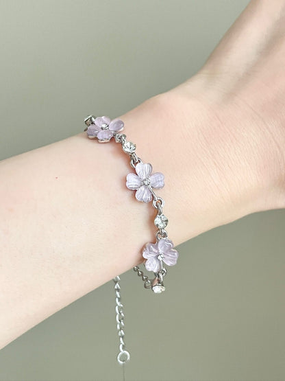 Bracelet with pink flower-shaped charms on a wrist against a neutral background