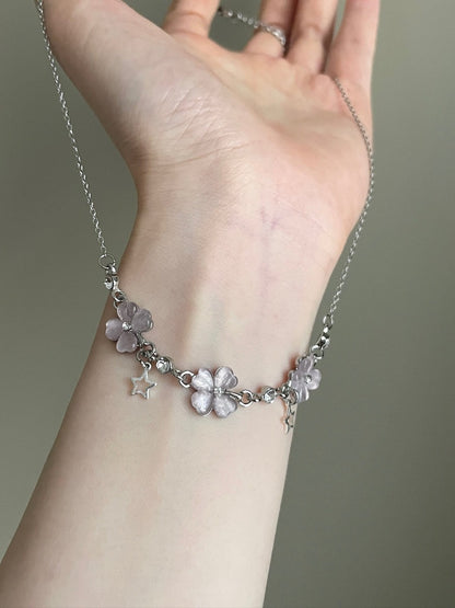 Silver bracelet with floral charms on a wrist against a neutral background