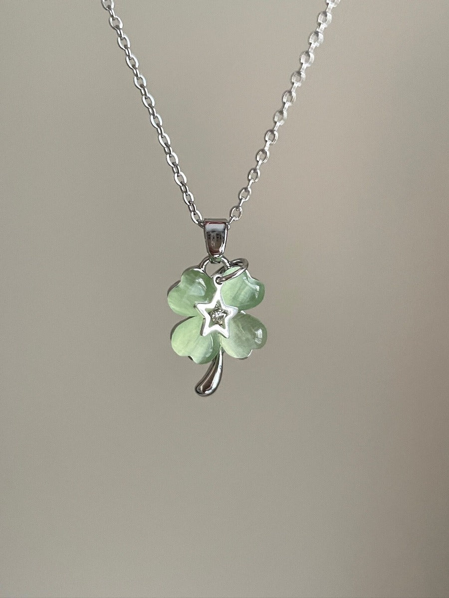 Necklace with a green four-leaf clover pendant on a plain background