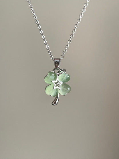 Necklace with a green four-leaf clover pendant on a plain background