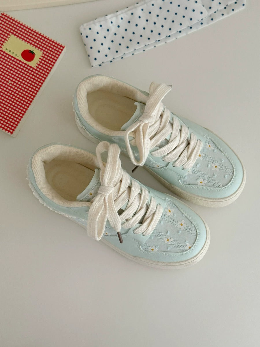 Light blue sneakers with white laces on a light surface.