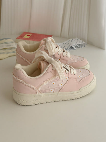 Pink sneakers with floral details on a light surface