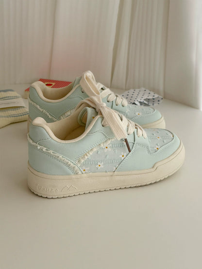 Pair of light blue sneakers with white laces on a neutral background