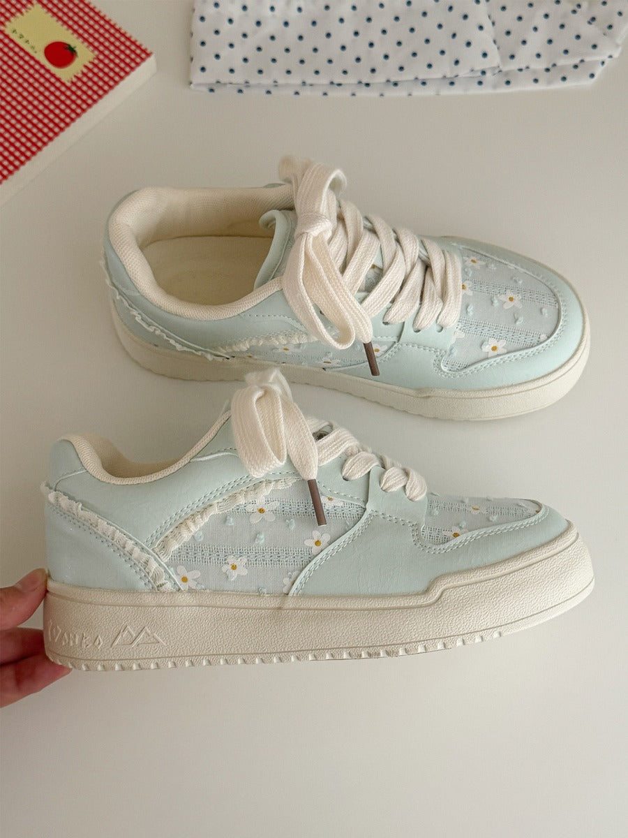 Light blue sneakers with white laces on a light gray background