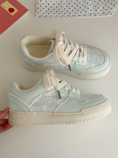 Light blue sneakers with white laces on a light gray background