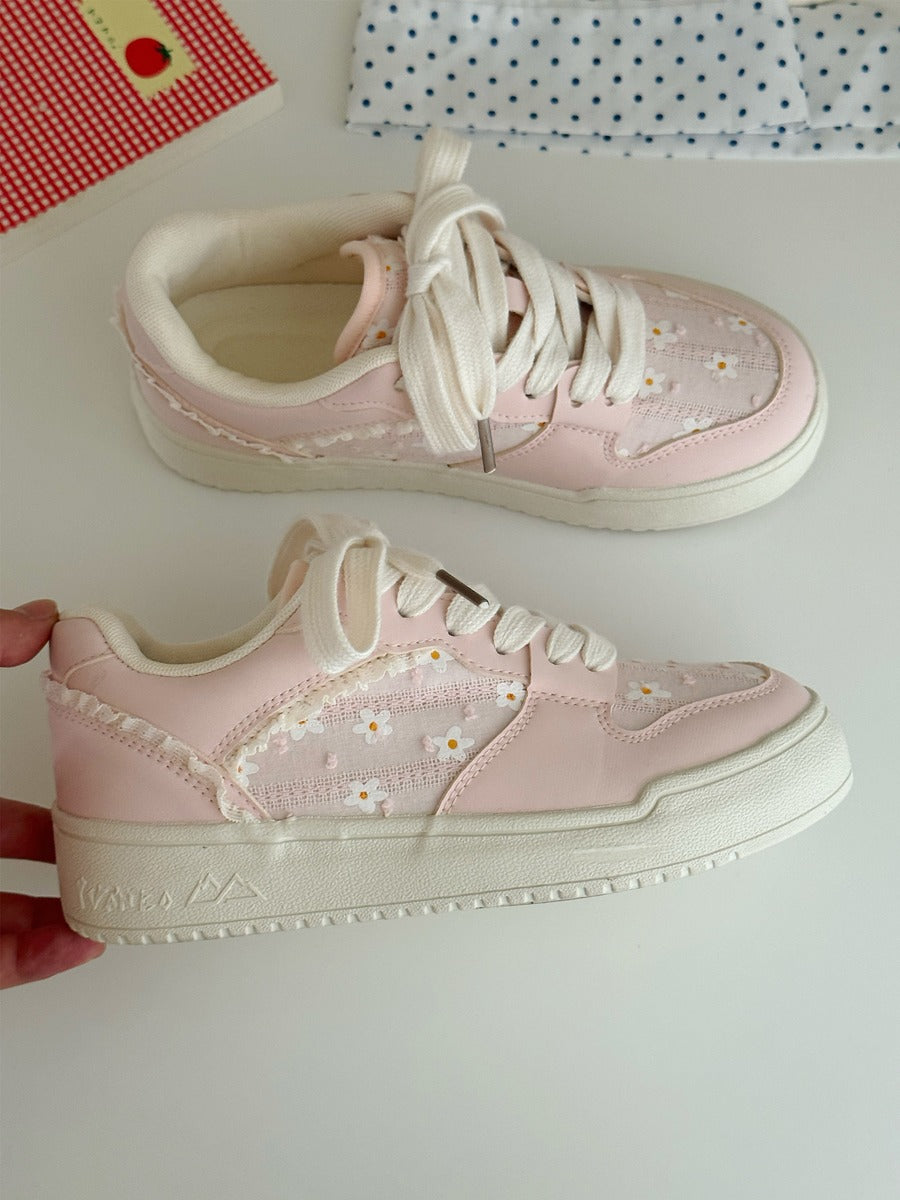 Pink sneakers with white laces and floral pattern on a light background