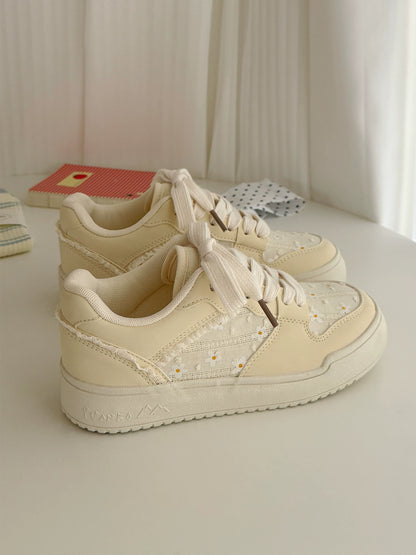Pair of beige sneakers on a light surface with a soft, blurred background