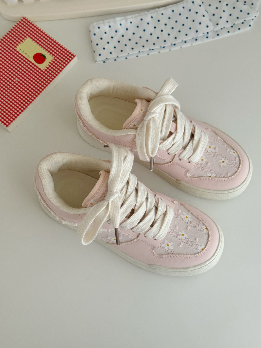 Pink high-top sneakers with white laces on a light surface.