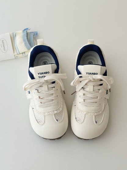 Pair of white sneakers with blue soles on a light gray background