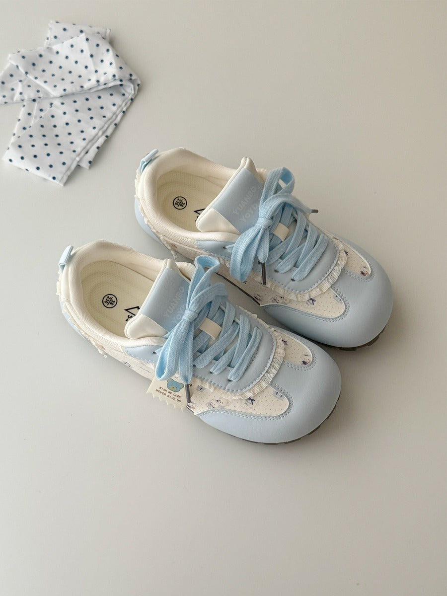 Pair of light blue and white baby shoes on a neutral background