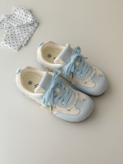 Pair of light blue and white baby shoes on a neutral background