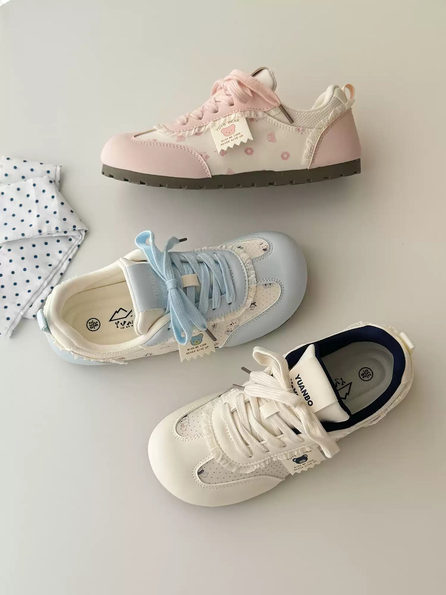 Three pairs of sneakers on a light gray surface with a white cloth.