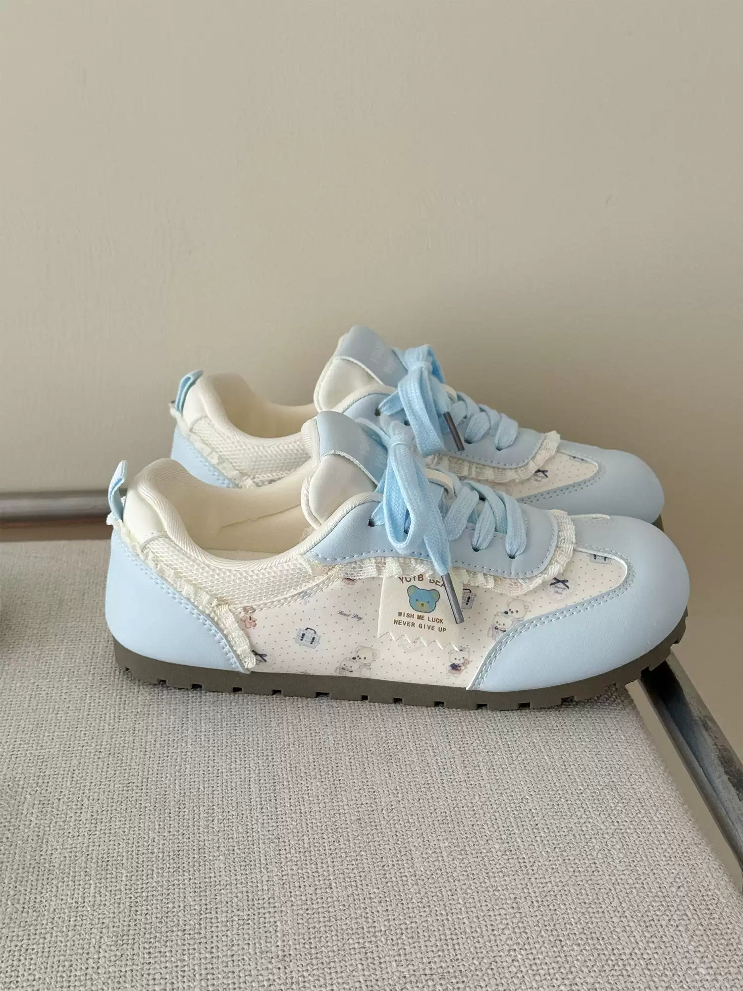 Pair of light blue sneakers with white laces on a neutral background