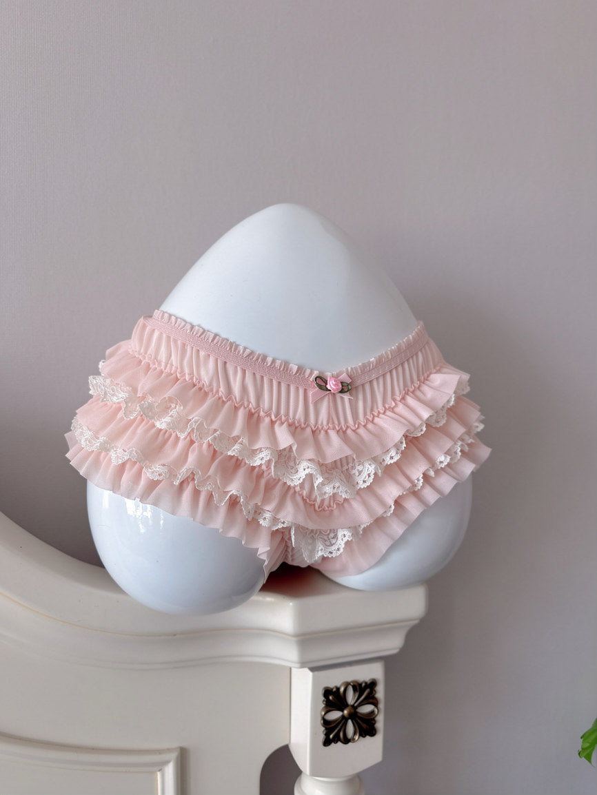 Pink ruffled baby bloomers on a white mannequin against a plain background